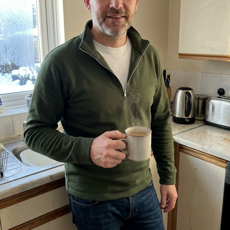 Man in the Darkwave Regal Pullover Sweater in Green holding a mug of coffee in his kitchen on a winter morning