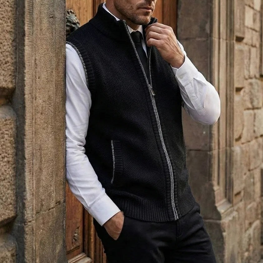 Man wearing the Elegant Full-Zip Sweater Vest in Black with a white shirt and tie, leaning in a stone doorway